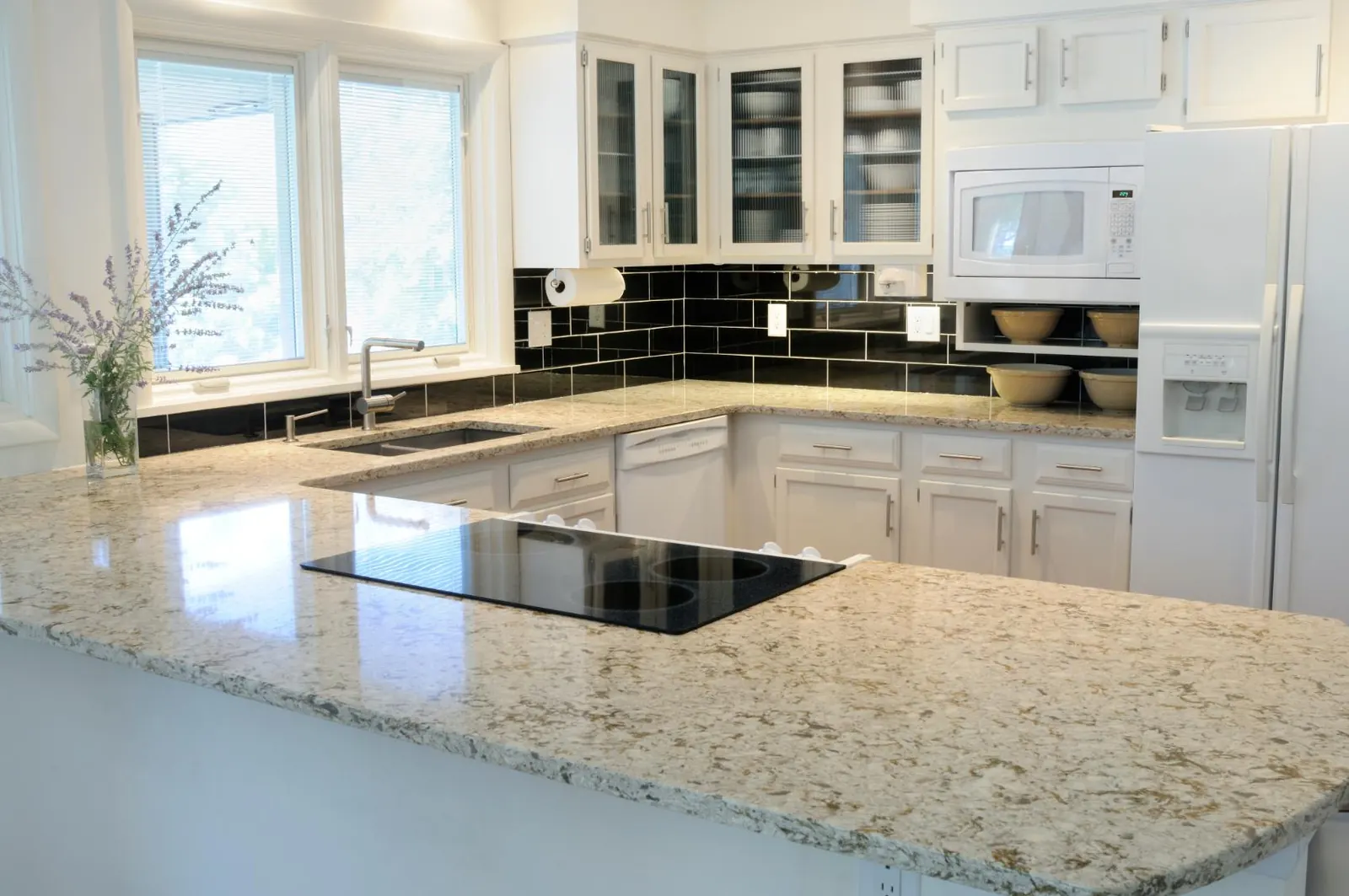 Speckled granite countertops with a cooktop in a white kitchen